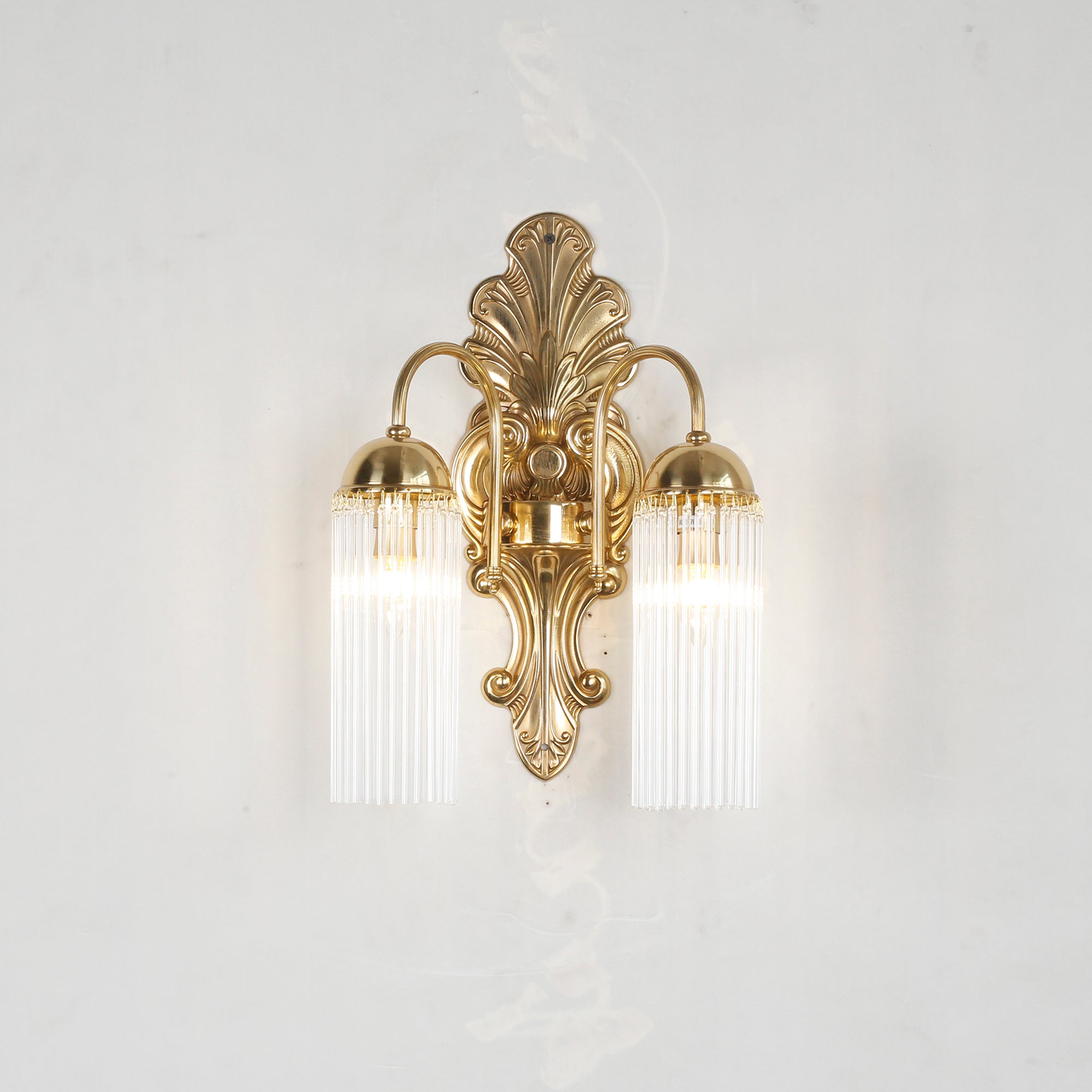 The Triest Wall Sconce against a dark wall to showcase the brass finish.