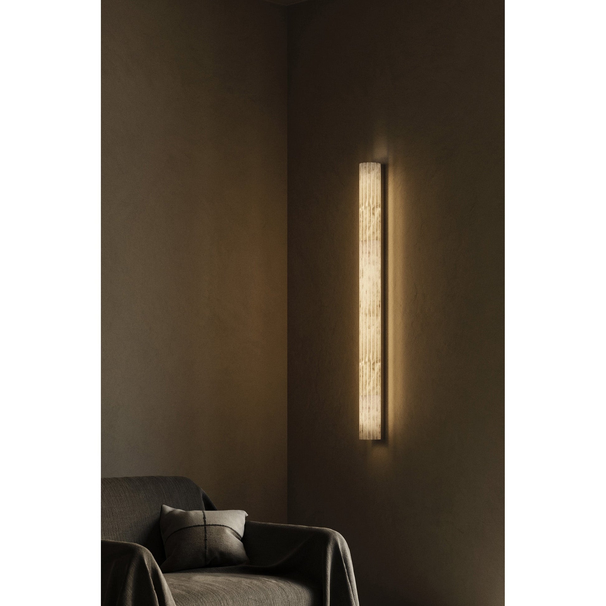 The wall sconce shown against a dark, textured wall for dramatic contrast.