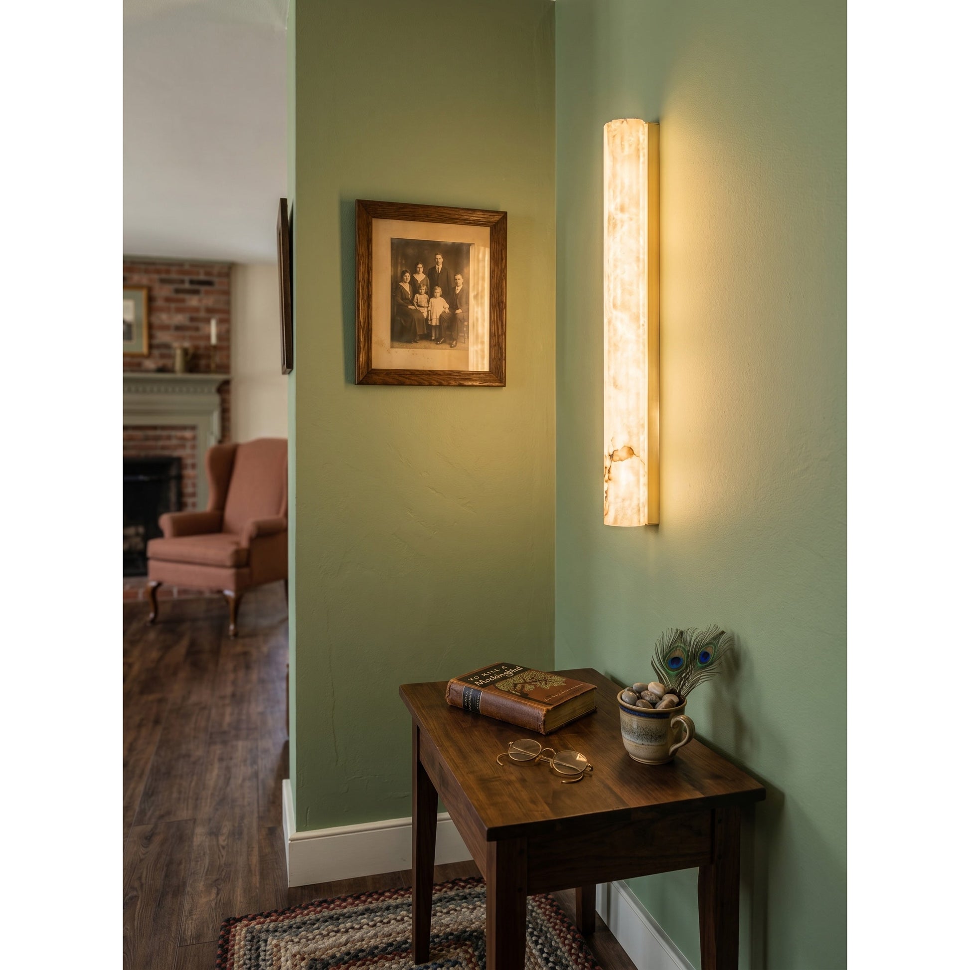The 50cm version of the vertical alabaster wall sconce against a neutral wall.