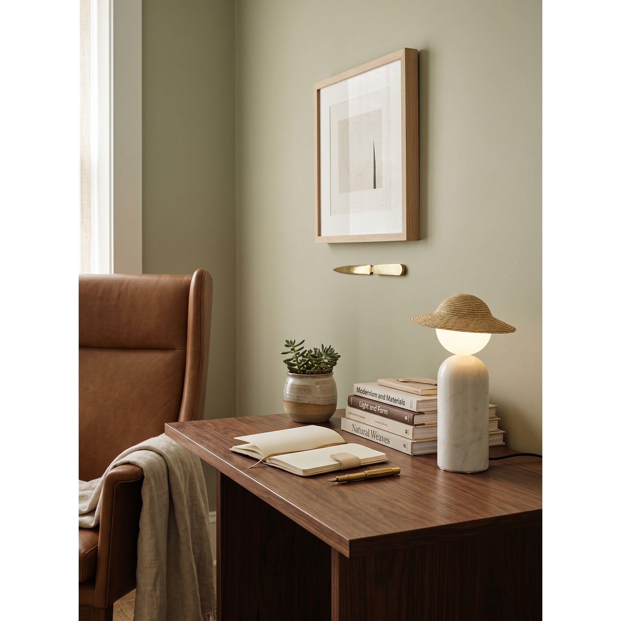 The Theros Table Lamp illuminating a bedside table with a warm glow.