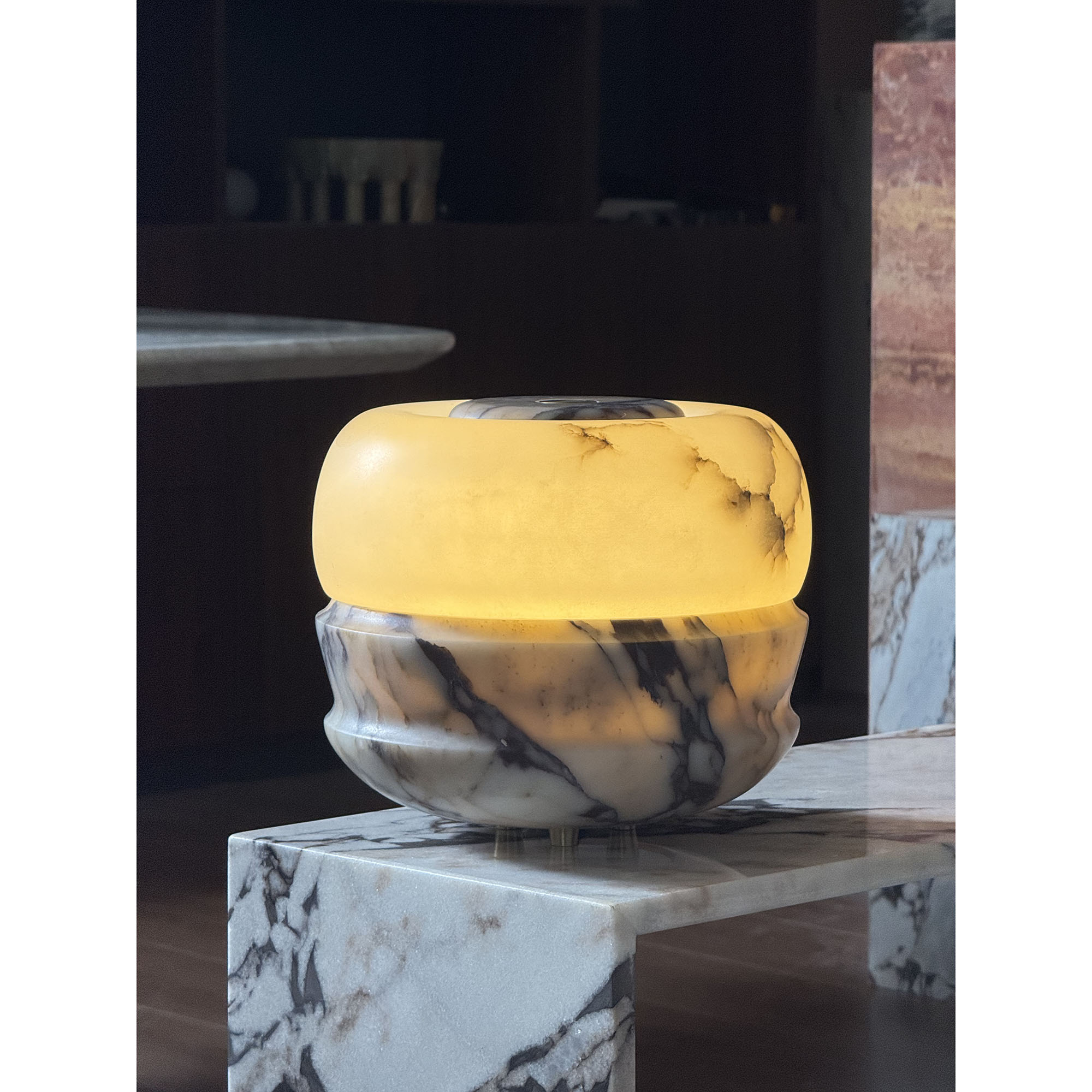 Ramson Stone Table Lamp in amber marble, casting a warm glow.