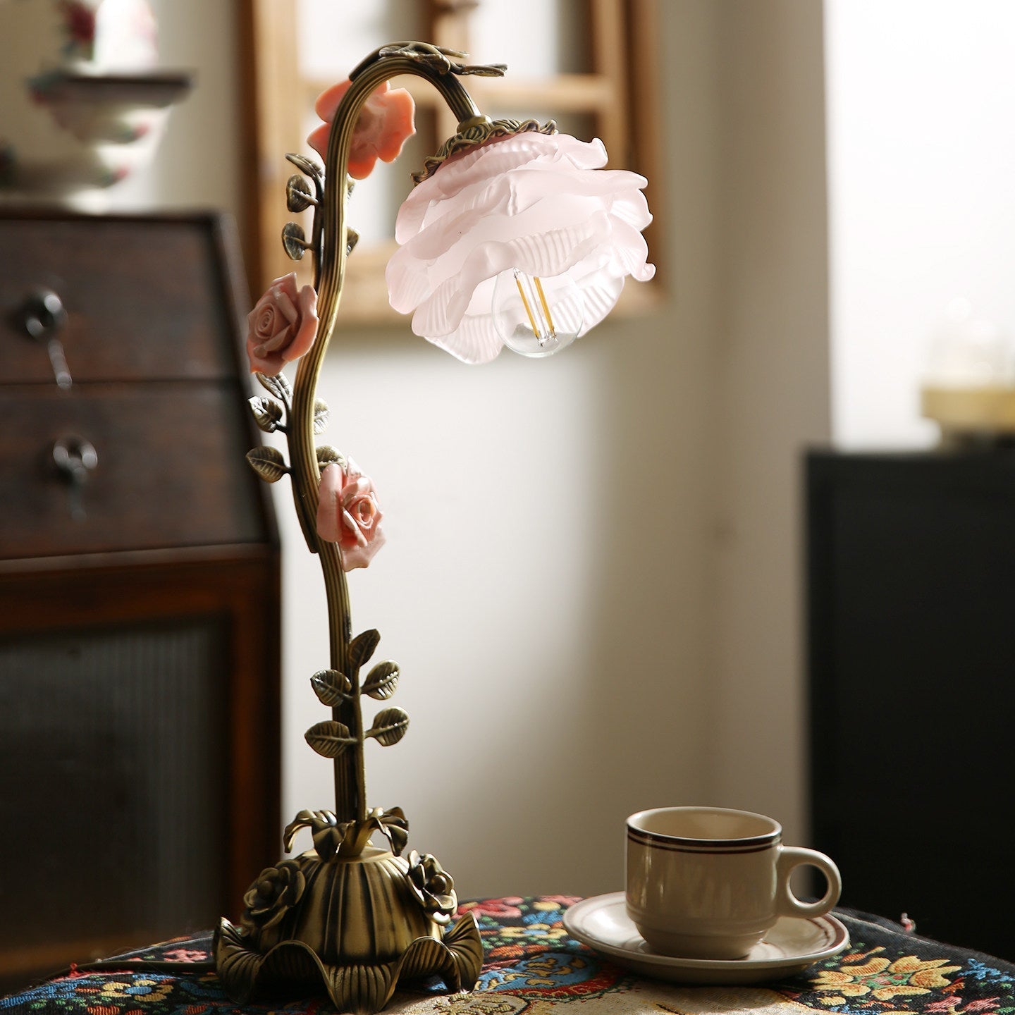 The Rosalie lamp illuminated in a dimly lit room, showcasing its warm glow.