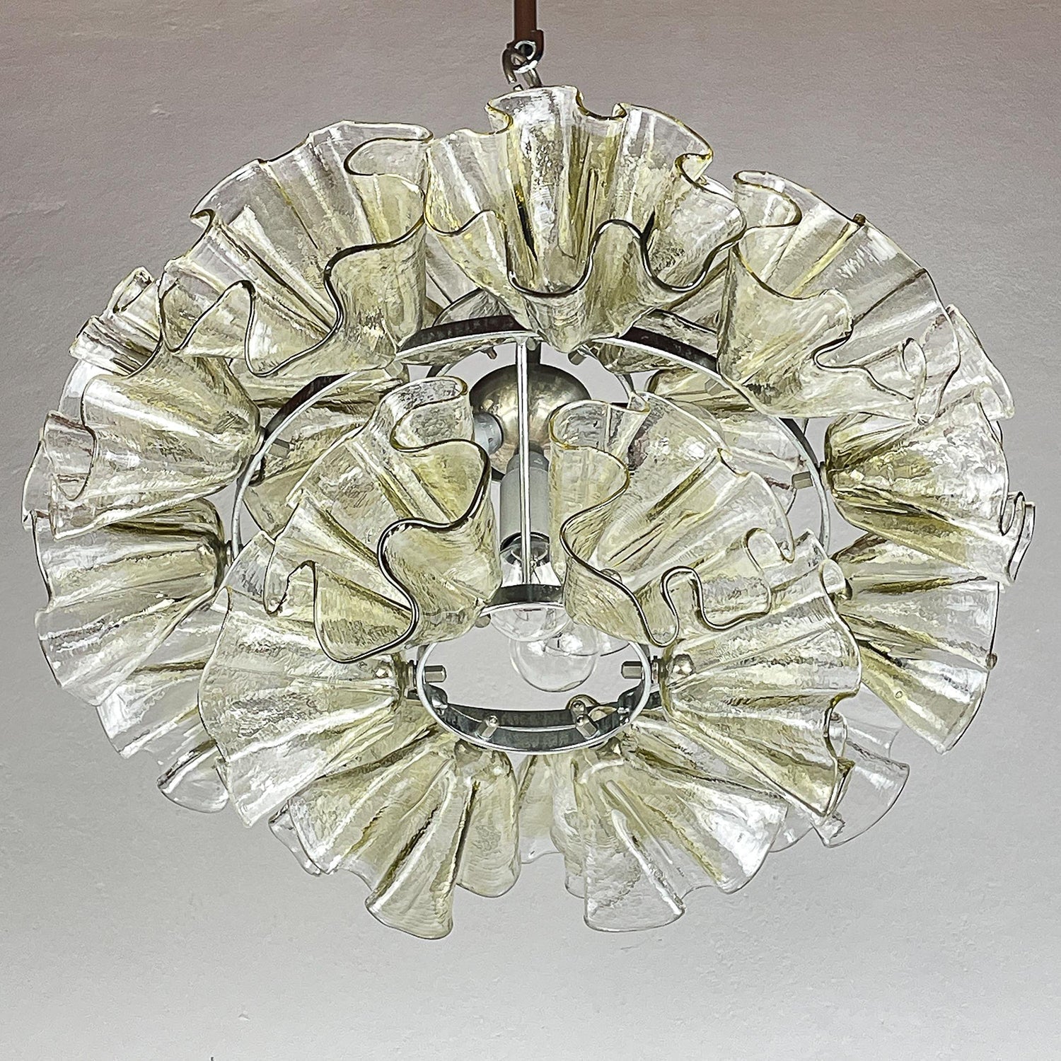 The chandelier illuminated in a dark room, casting a warm glow.