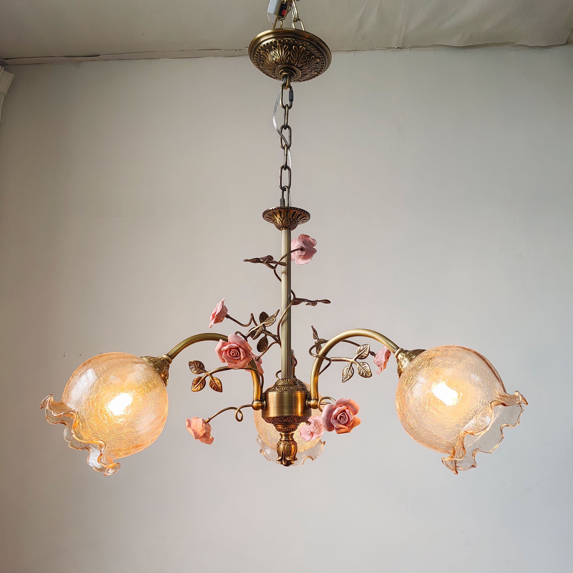 Close-up of the Serenade Chandelier's ceramic flower and brass detail.