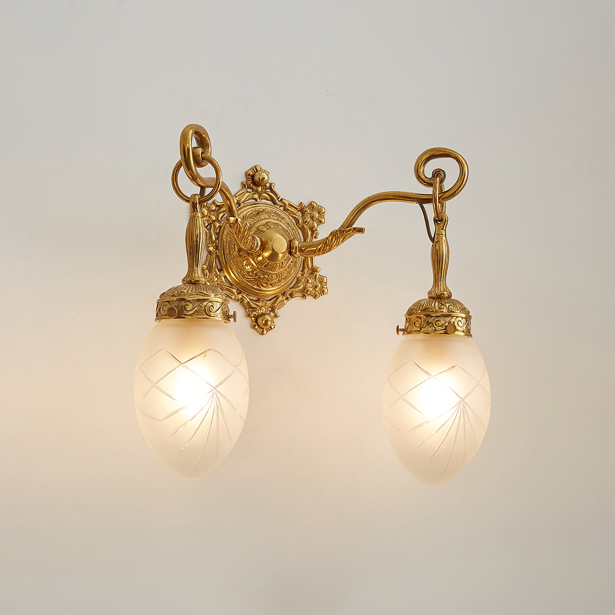 Detail shot of the polished brass body and arm of the wall lamp.