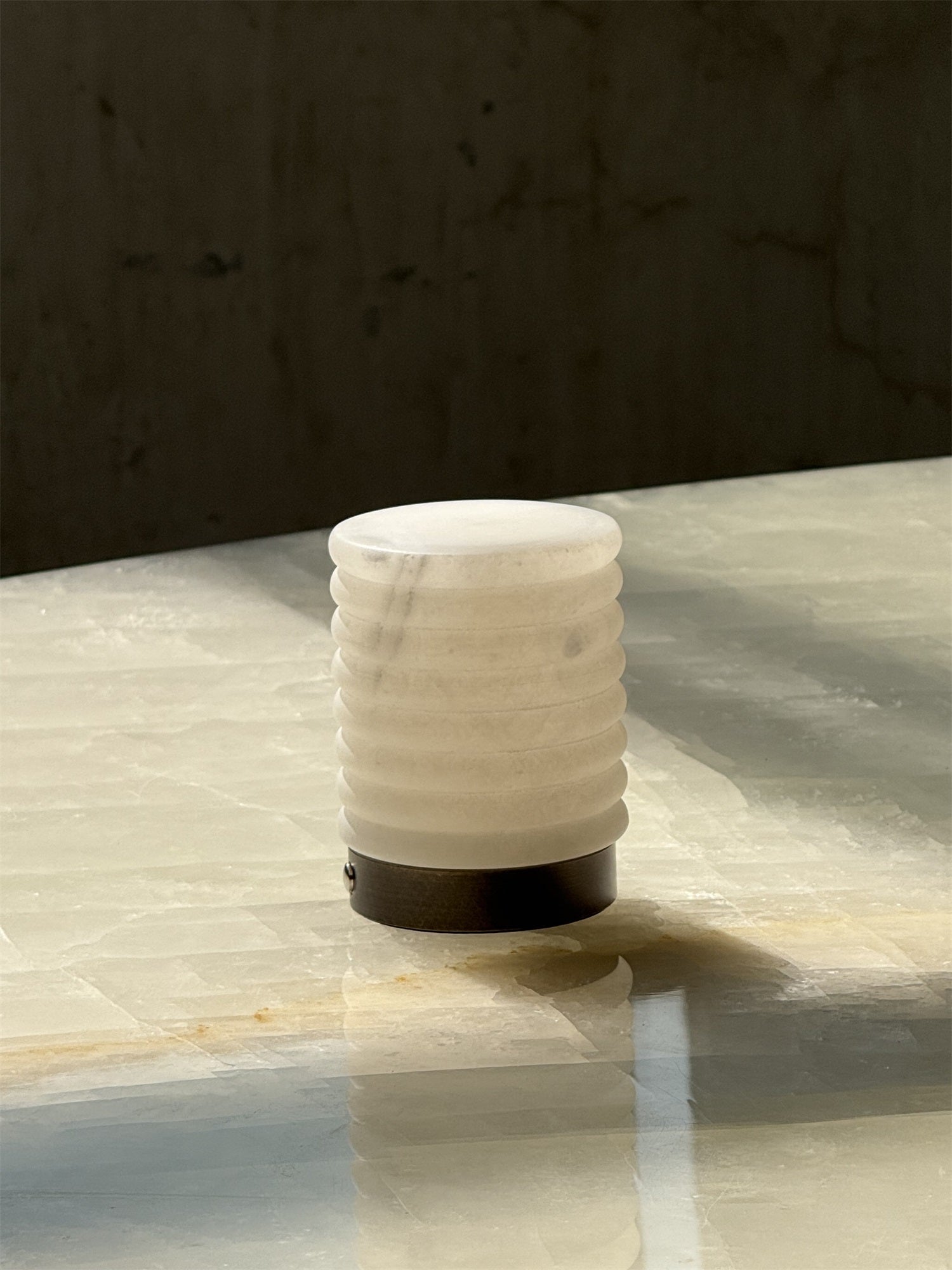 The portable alabaster table lamp being held to show its size and battery-powered feature.
