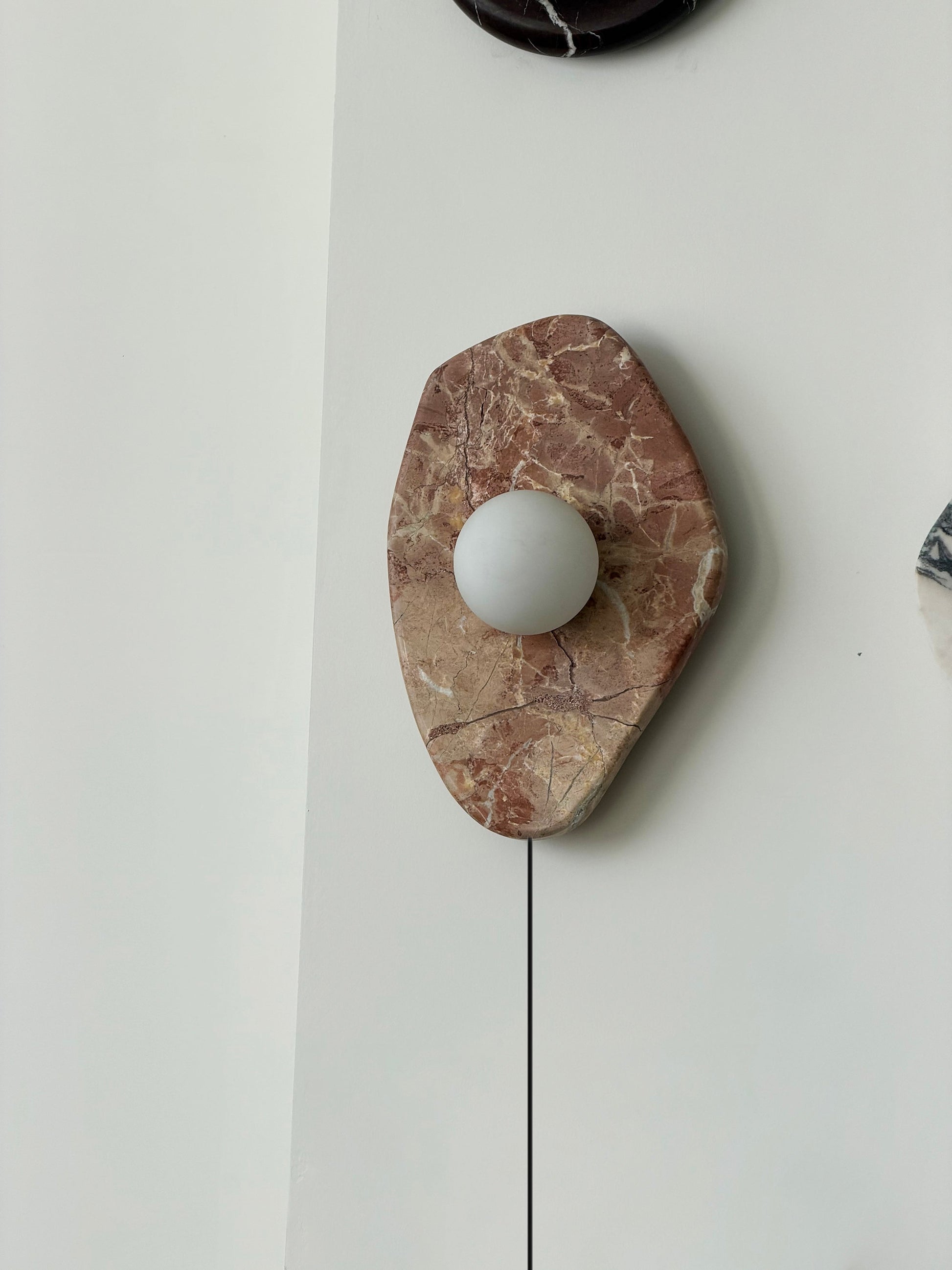 The wall lamp used as a bedside reading light in a modern bedroom.