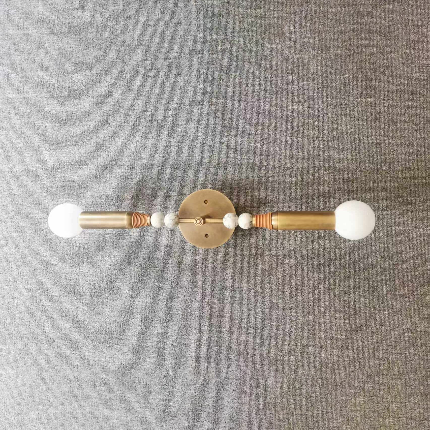 Toam Double Wall Lamp against a dark wall.