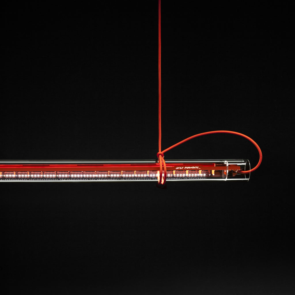 The clear tubular lamp illuminating a wooden surface below.