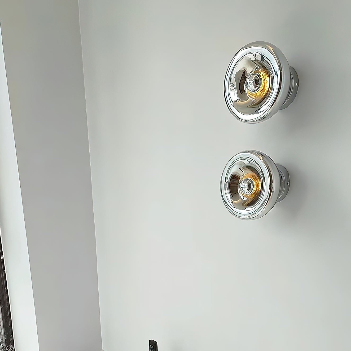 Void Surface Sconce installed on a dark wall, casting a warm glow.