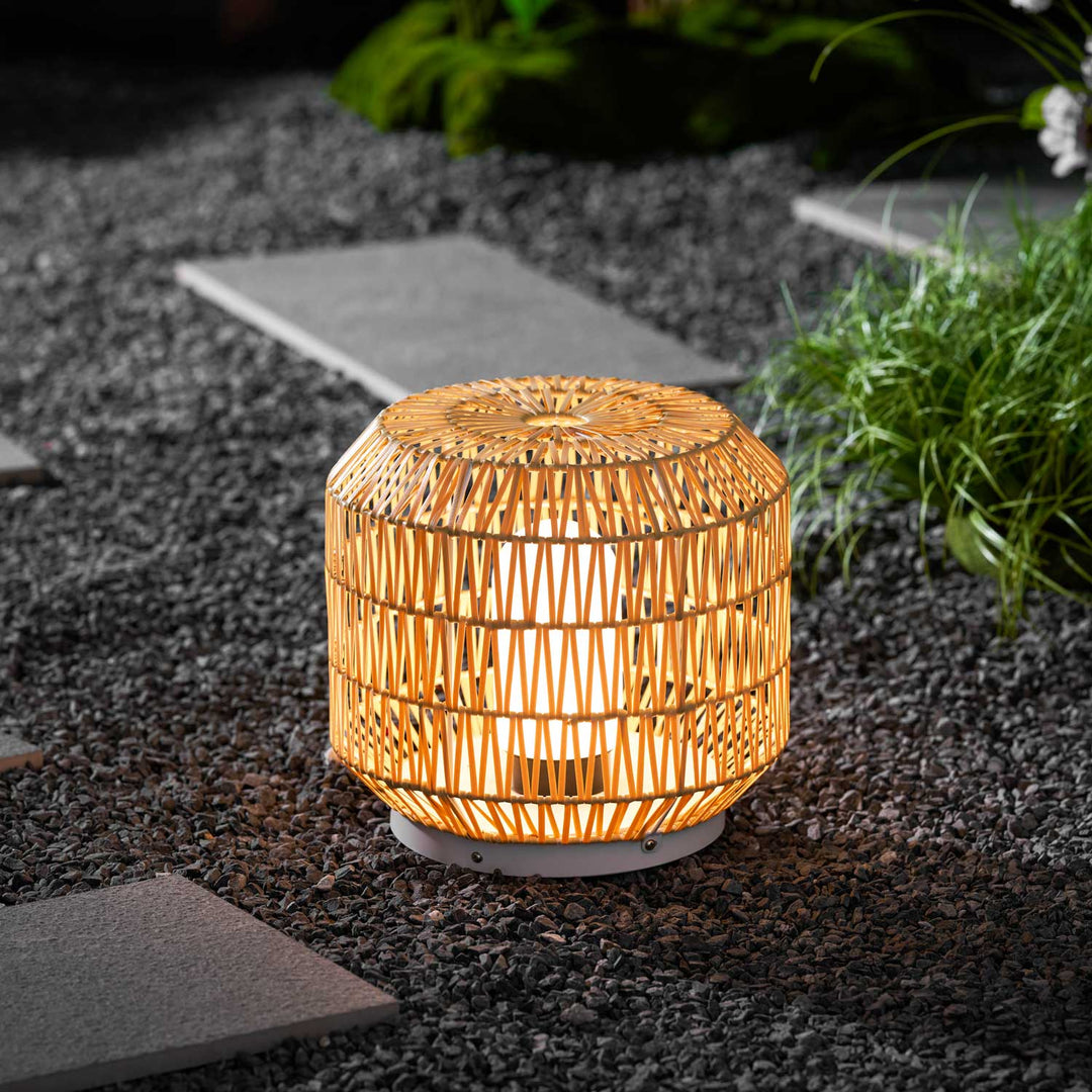 The outdoor lamp shown illuminating a patio setting at dusk.