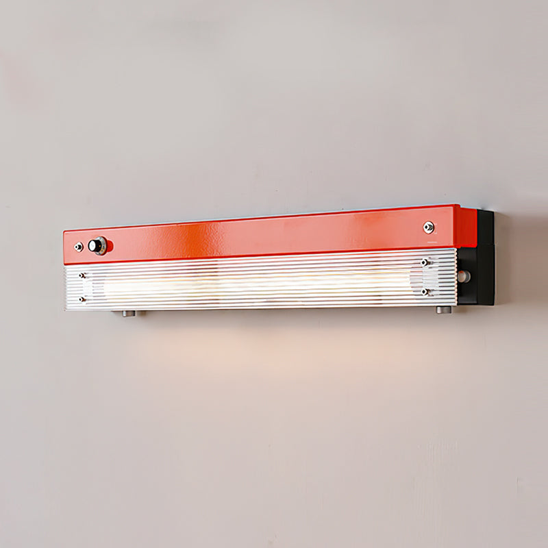 The red Totem Wall Lamp against a light-colored wall.